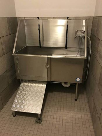 A stainless steel sink in a bathroom with a step in front of it